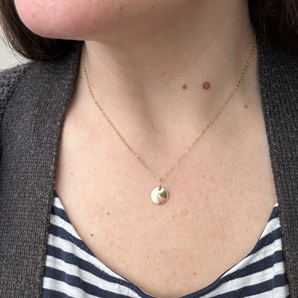 Model wearing initial charm on a simple chain showcasing handmade letter charm jewelry sustainable brand
