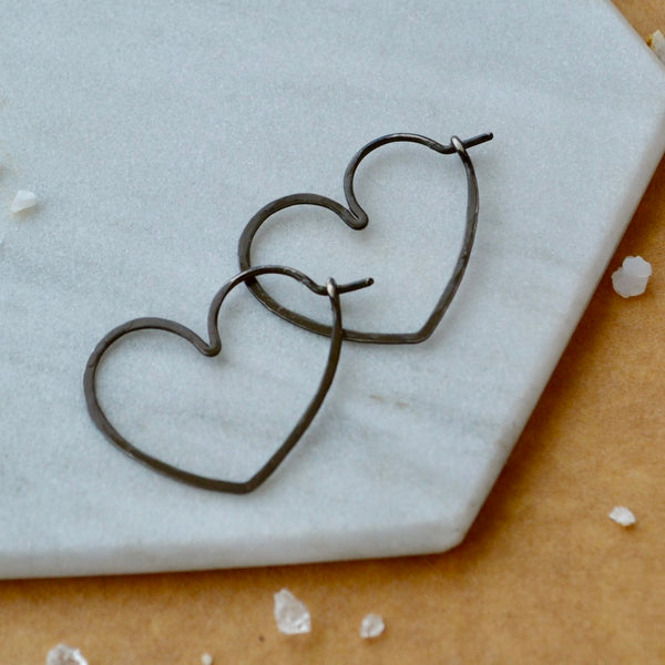 black Heart-shaped earrings on a marble surface