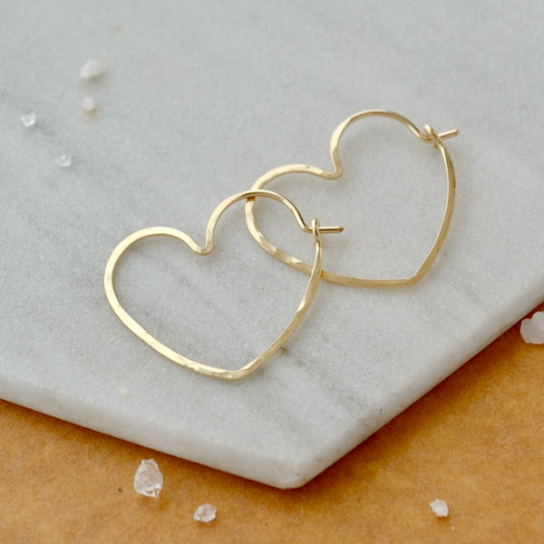 Gold heart-shaped hoop earrings on a marble surface