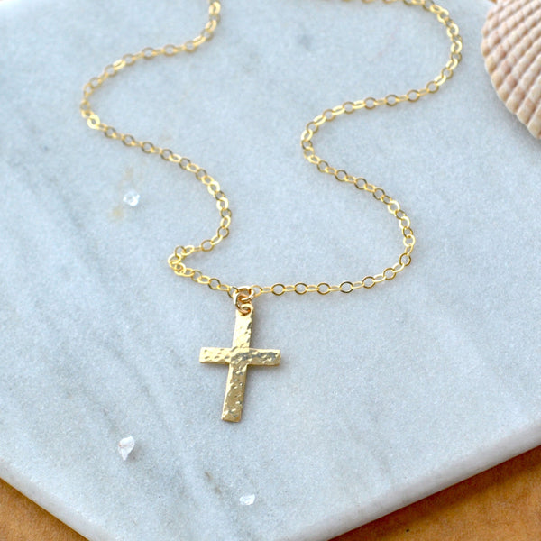 Gold cross necklace on a marble surface