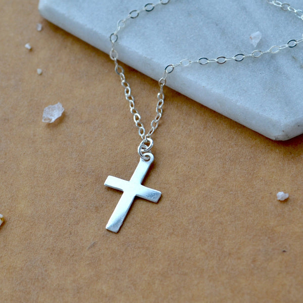 Simple Silver cross necklace on a marble surface