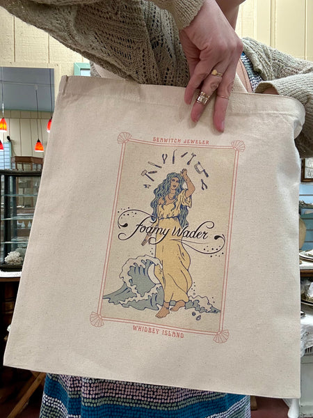 Tote bag with Foamy Wader logo, text that reads "seawitch jeweler" and "whidbey island", and art nouveau-style tarot card like imagery on a square cotton canvas bag.