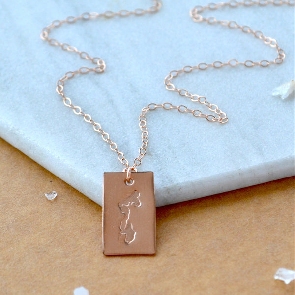 Rose gold necklace with a rectangular Whidbey Island pendant on a marble surface