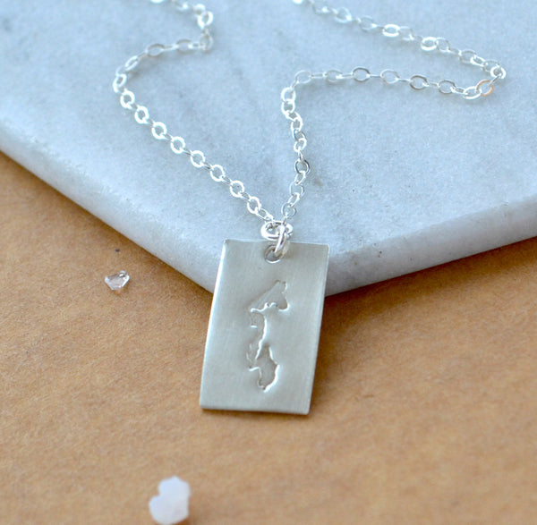 Silver necklace with a rectangular Whidbey Island pendant on a marble surface
