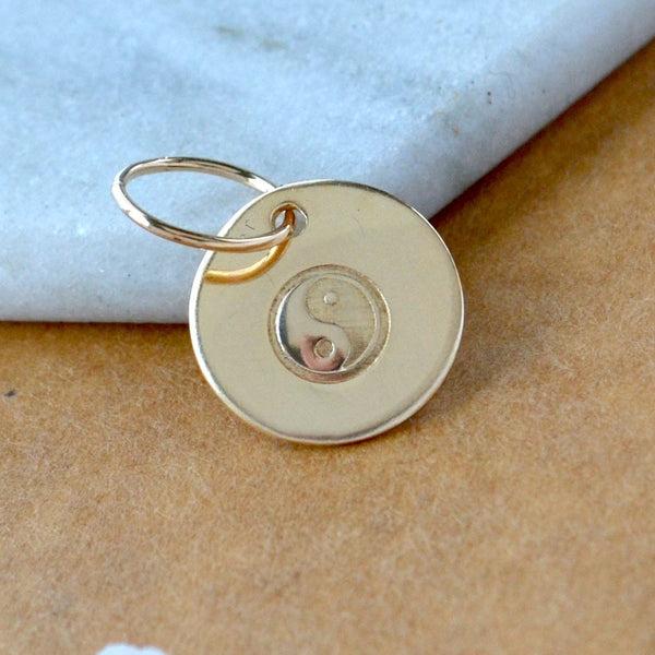 Gold pendant with yin yang symbol on a marble surface