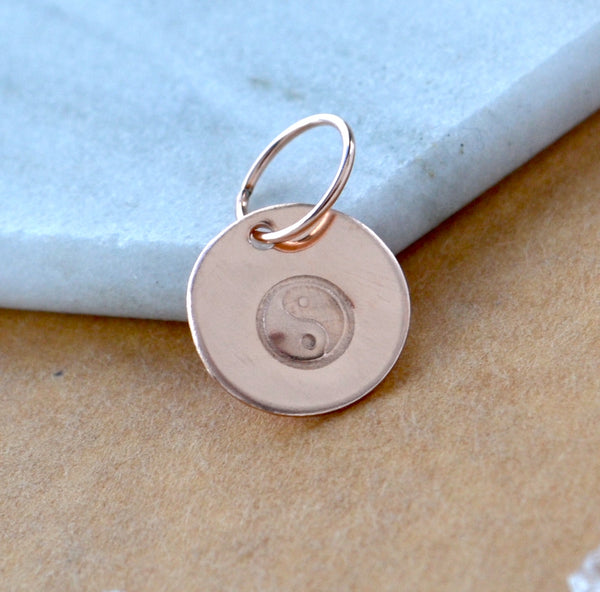 Rose gold pendant with yin yang symbol on a marble surface