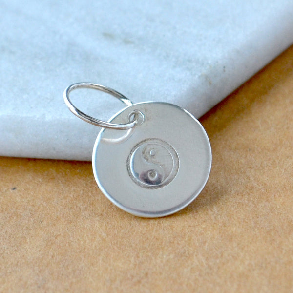 Silver pendant with yin yang symbol on a marble surface